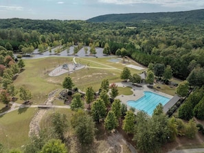Vista aérea de uma área residencial com piscina, quadras de tênis e um ambiente semelhante a um parque.