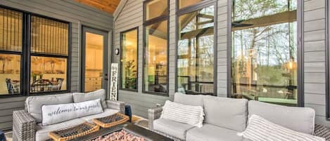 A covered outdoor seating area with a fireplace, two sofas, and a coffee table.