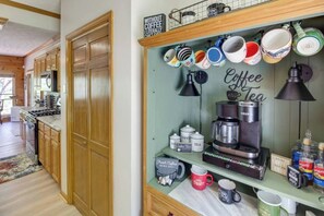 A kitchen with wooden cabinets, a coffee station with a Keurig machine, and various mugs and containers.