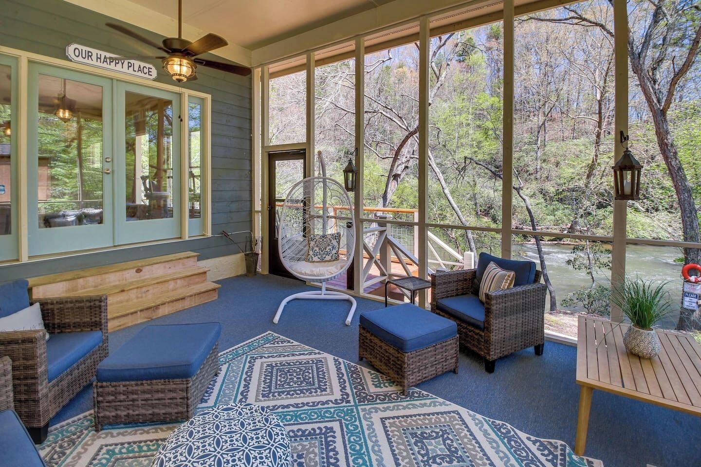 A covered porch with wicker furniture, a bicycle, and a view of a river.