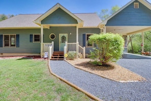 A two-story house with a front porch, a small front yard, and a gravel driveway.