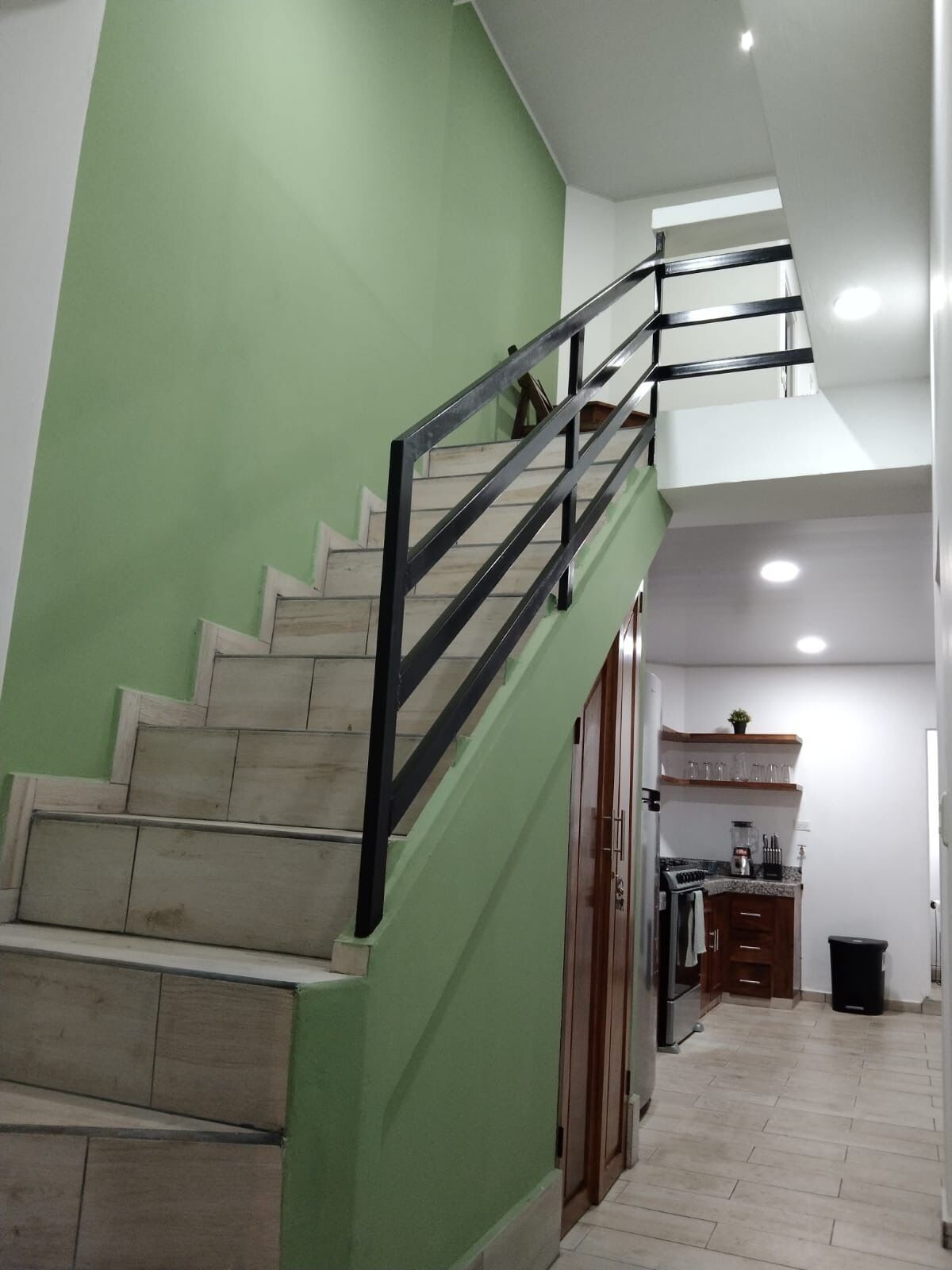 A staircase with green walls and a black railing leading to a second floor.