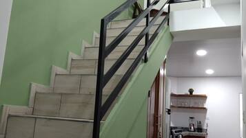 A staircase with green walls and a black railing leading to a second floor.