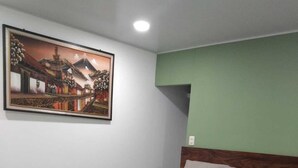 Un dormitorio con cama, pared verde y un cuadro enmarcado.