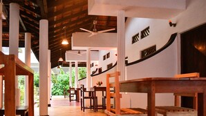 A church interior with wooden pews, white columns, and a ceiling fan.