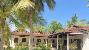 A traditional building with a tiled roof, surrounded by palm trees and potted plants.