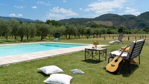 A pool area with a view of hills, a guitar, and a bench. - A typical Italian Villa in the center of Italy.  (spoleto)
