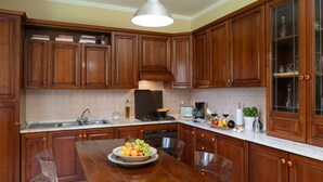 A kitchen with wooden cabinets, a stainless steel sink, a stove, and a dining table with a fruit bowl. - A typical Italian Villa in the center of Italy.  (spoleto)