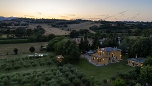 A two-story house with a spacious backyard, surrounded by lush greenery and rolling hills in the background. - A typical Italian Villa in the center of Italy.  (spoleto)