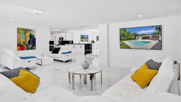 Ein modernes Wohnzimmer mit weißen Sofas, einem Couchtisch und Kunstwerken an den Wänden.