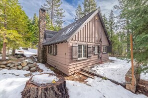 Eine Holzhütte mit Steinkamin und verschneiter Umgebung.