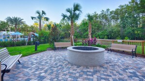 A paved patio with benches, a circular planter, and palm trees. - Vacation Village at Parkway. 2 bedroom, 2 bath condo that can be separate units. (Kissimmee)