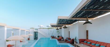 A modern outdoor pool area with a long pool, sun loungers, and umbrellas.