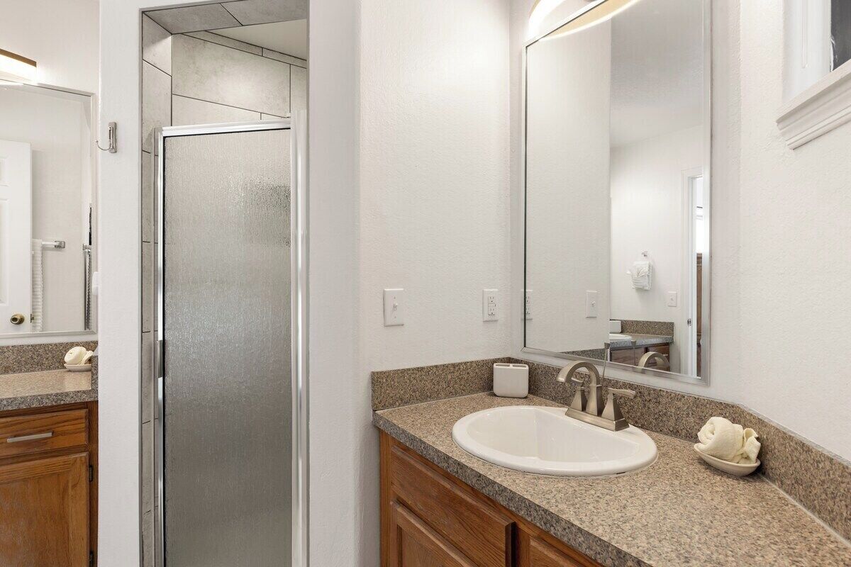 A bathroom with a shower, sink, and mirror.