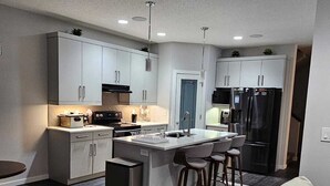 Una cucina moderna con mobili grigi, un'isola centrale con sgabelli da bar, forno integrato e frigorifero.