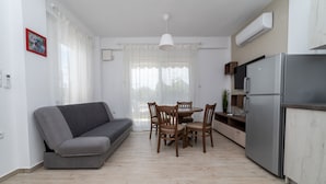 A compact living space with a sofa, dining table, chairs, and a refrigerator. - Danai Maisonettes Ofriniou  (Pangaio)