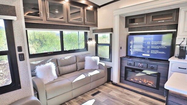 A cozy RV interior with a sofa, a fireplace, and a television. - Sonoran Serenity (Tucson)