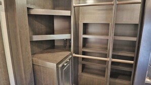 A walk-in closet with wooden shelving and a metal ladder. - Sonoran Serenity (Tucson)