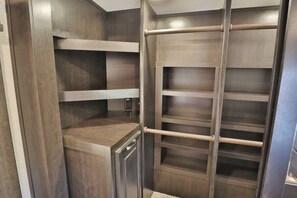 Un vestidor con estantes de madera y una escalera de metal.