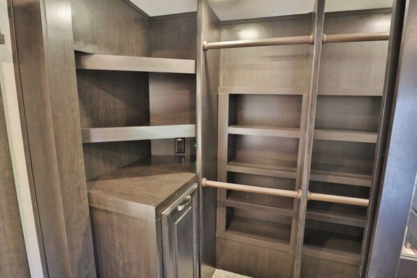 A walk-in closet with wooden shelving and a metal ladder.