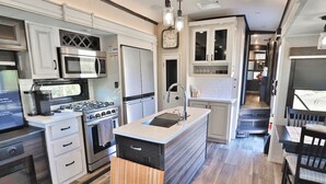 A modern kitchen with a central island, built-in appliances, and a dining area with a table and chairs. - Sonoran Serenity (Tucson)