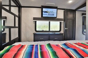 Una habitación de hotel con cama, televisor sobre una ventana y una puerta.