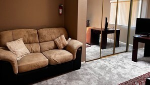 A living room with a brown leather sofa, a wooden desk, a television, and a sliding glass door. - Adorable Home for Family. (Stockton)