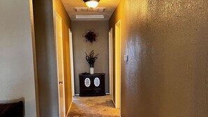 A hallway with a carpeted floor, a wall clock, and a decorative wall piece. - Adorable Home for Family. (Stockton)
