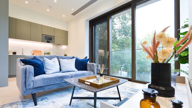 A modern living room with a grey sofa, a coffee table, and a large window with a view of greenery. - Haverstock Hill Serviced Apartments by Concept Apartments (London)