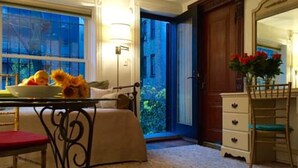 Un dormitorio con cama, mesita de noche con lámpara, cómoda, silla y ventana con vistas al verdor.