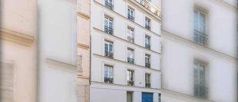 A multi-story building with a white facade, multiple windows, and balconies.