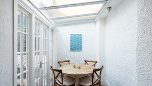 Un tavolo rotondo in legno con quattro sedie, un piccolo oggetto decorativo e un pannello murale azzurro con motivo.