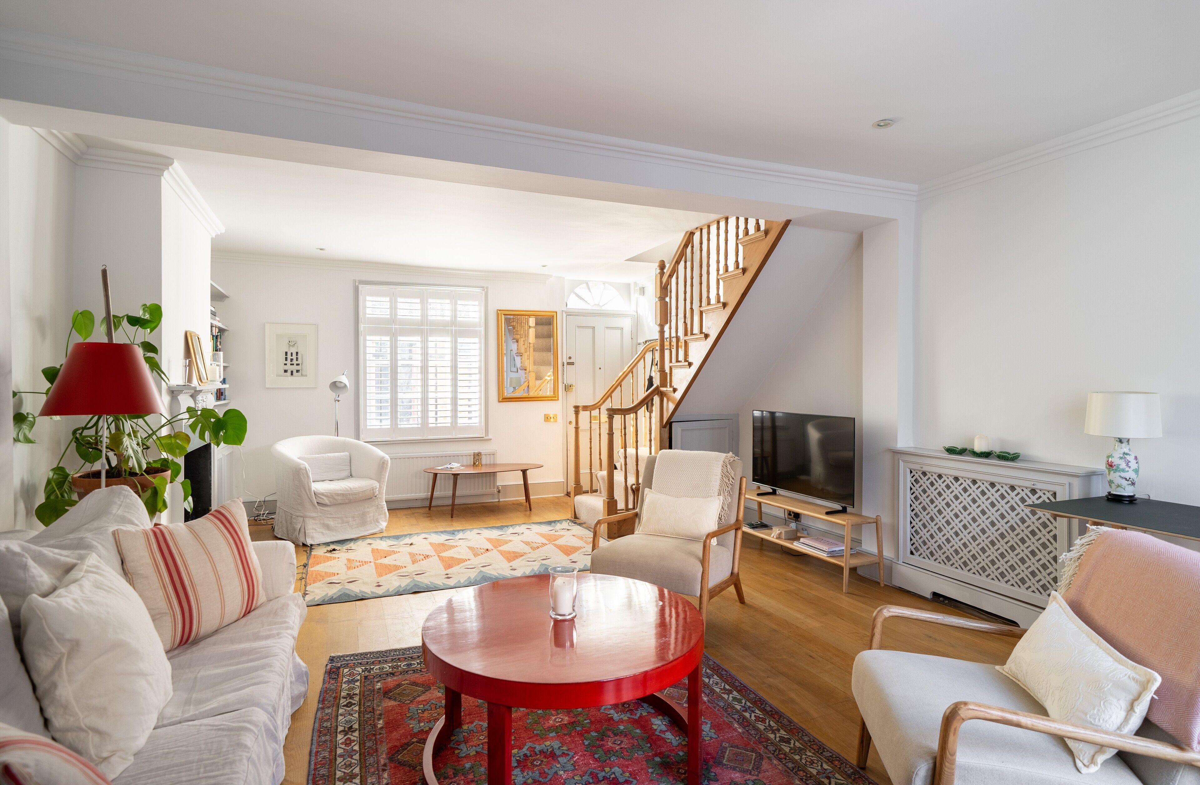 A spacious living room with a staircase, a TV, and a cozy seating area.