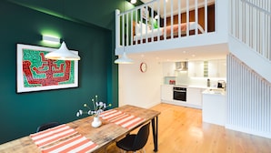 A modern apartment with a dining area, kitchen, and a loft bedroom.