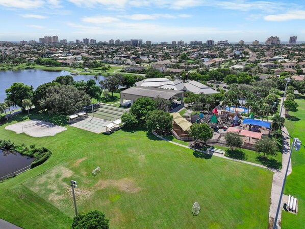 An aerial view of a residential area with a large building, a playground, and a body of water. - Pet-friendly Waterfront Home With Pool, spa and Dock (Marco Island)