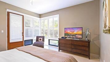 A bedroom with a bed, a TV, a dresser, and a chair.