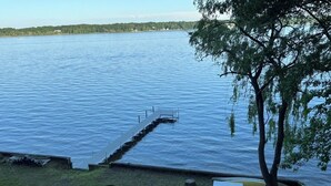 A lakeside dock with a wooden walkway leading to the water, a green kayak, and a picnic table. - The Perfect Place: Close to town, with 100' of private lake frontage. (Montague)