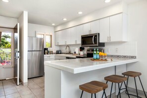 A modern kitchen with white cabinets, stainless steel appliances, and a large island with stools.