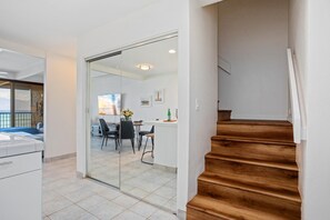 Un interior moderno con una escalera que conduce a un comedor, una cocina y una sala de estar con vistas.