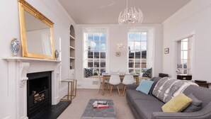 A living room with a fireplace, a sofa, a dining table with chairs, and a chandelier.