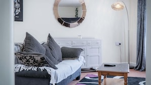 A bedroom with a bed, a dresser, a mirror, a floor lamp, and a rug.