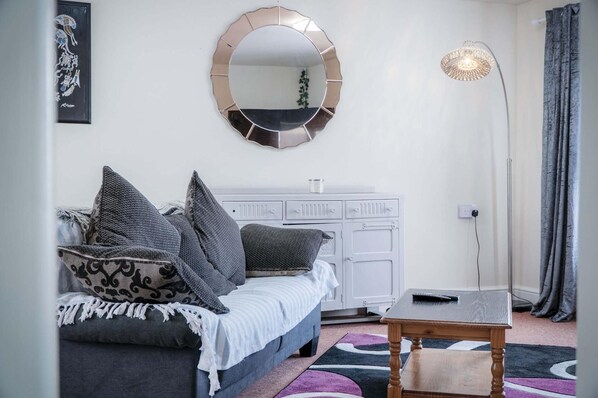 A bedroom with a bed, a dresser, a mirror, a floor lamp, and a rug.