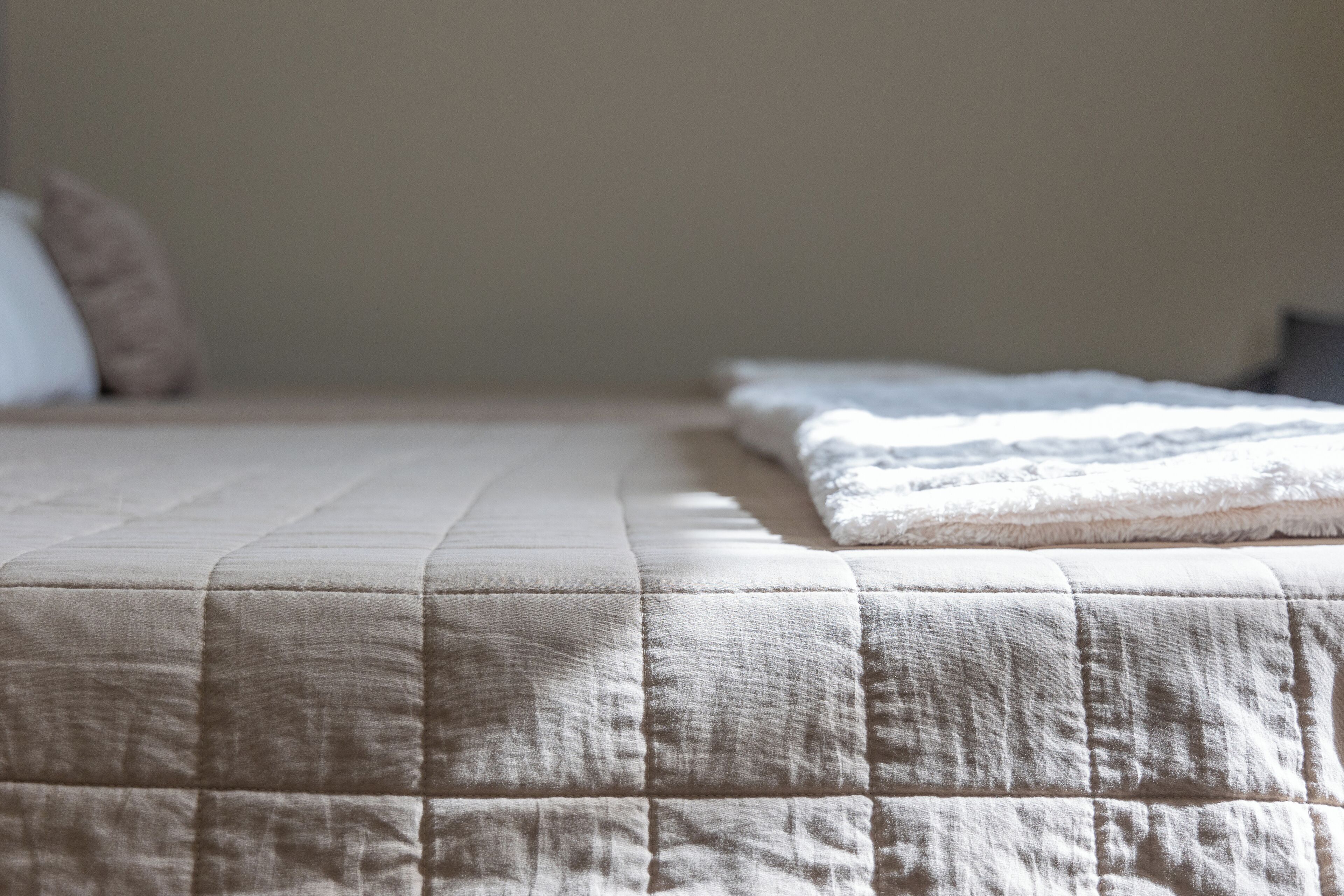 Una cama bien hecha con cubrecolcha acolchada y almohadas.