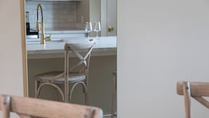 Una cocina con encimera blanca, una silla de madera y un grifo metálico.