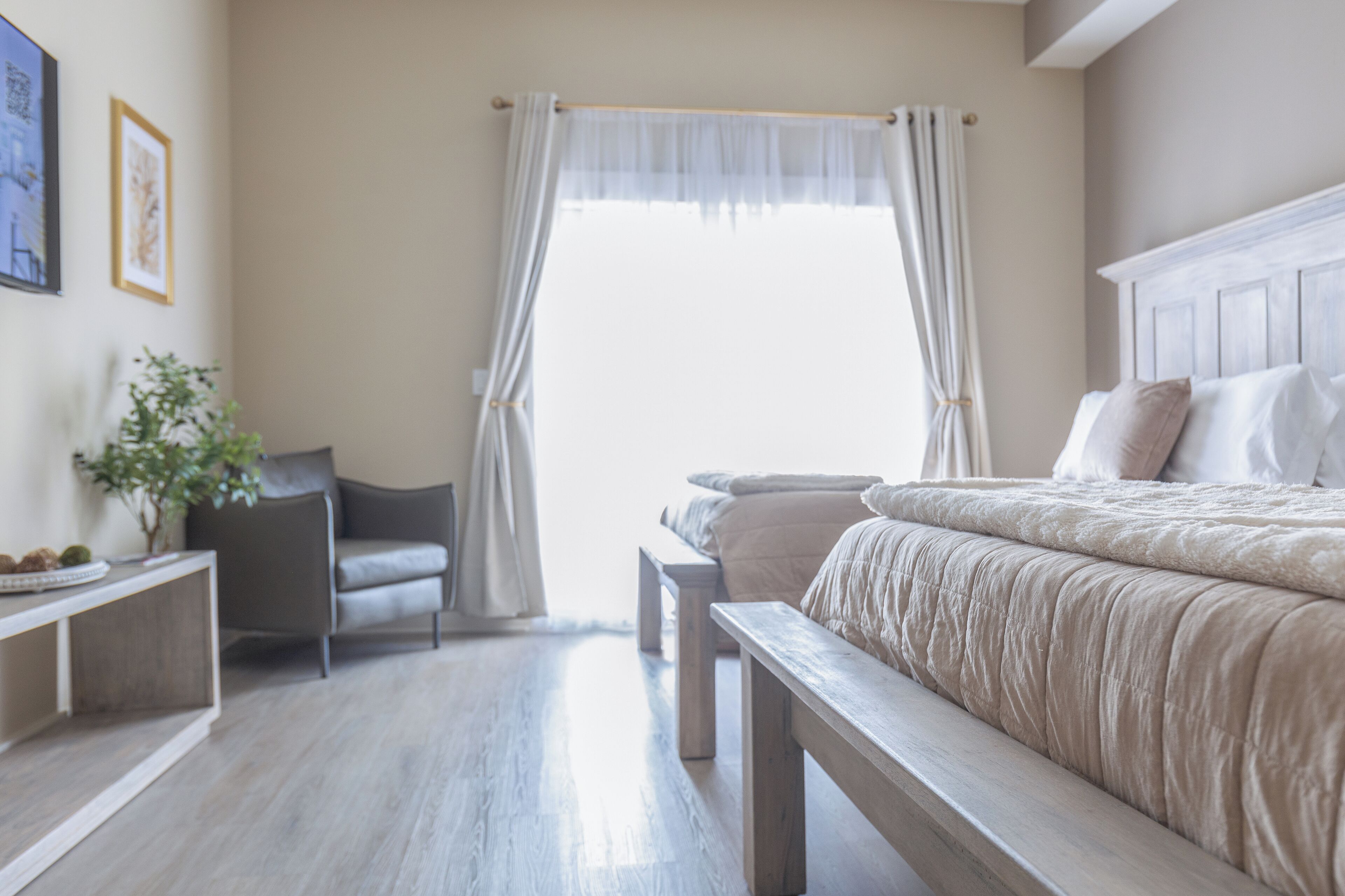 Un dormitorio con una cama, una silla, una mesita de noche y una ventana con cortinas.