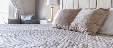 A neatly made bed with a patterned bedspread, a bedside lamp, and a nightstand with a lamp.