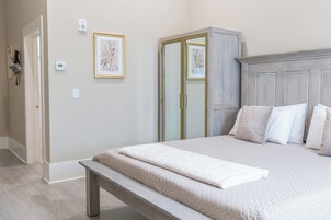 A bedroom with a bed, a bench, a wardrobe, and two framed pictures on the wall.