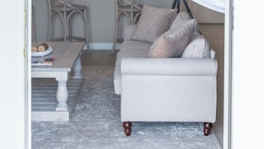 Una sala de estar moderna con un sofá, una mesa de centro y un comedor con sillas, y una cocina al fondo.