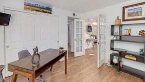A spacious room with a wooden dining table, a white door, and a bookshelf with decorative items. - Premier location in Scottsdale close to Old town & Open- HEATED pool & jacuzzi😎 (Paradise Valley)