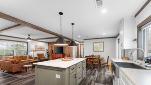 Un'ampia cucina con una grande isola, travi in legno a soffitto e zona pranzo con tavolo e sedie.
